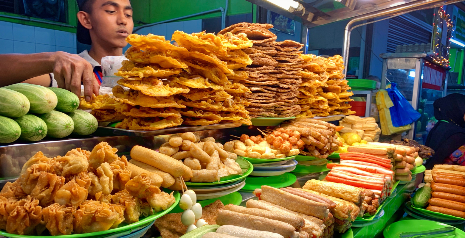 Night market with lots of Malaysian food stacked on a table for a piece on the topic