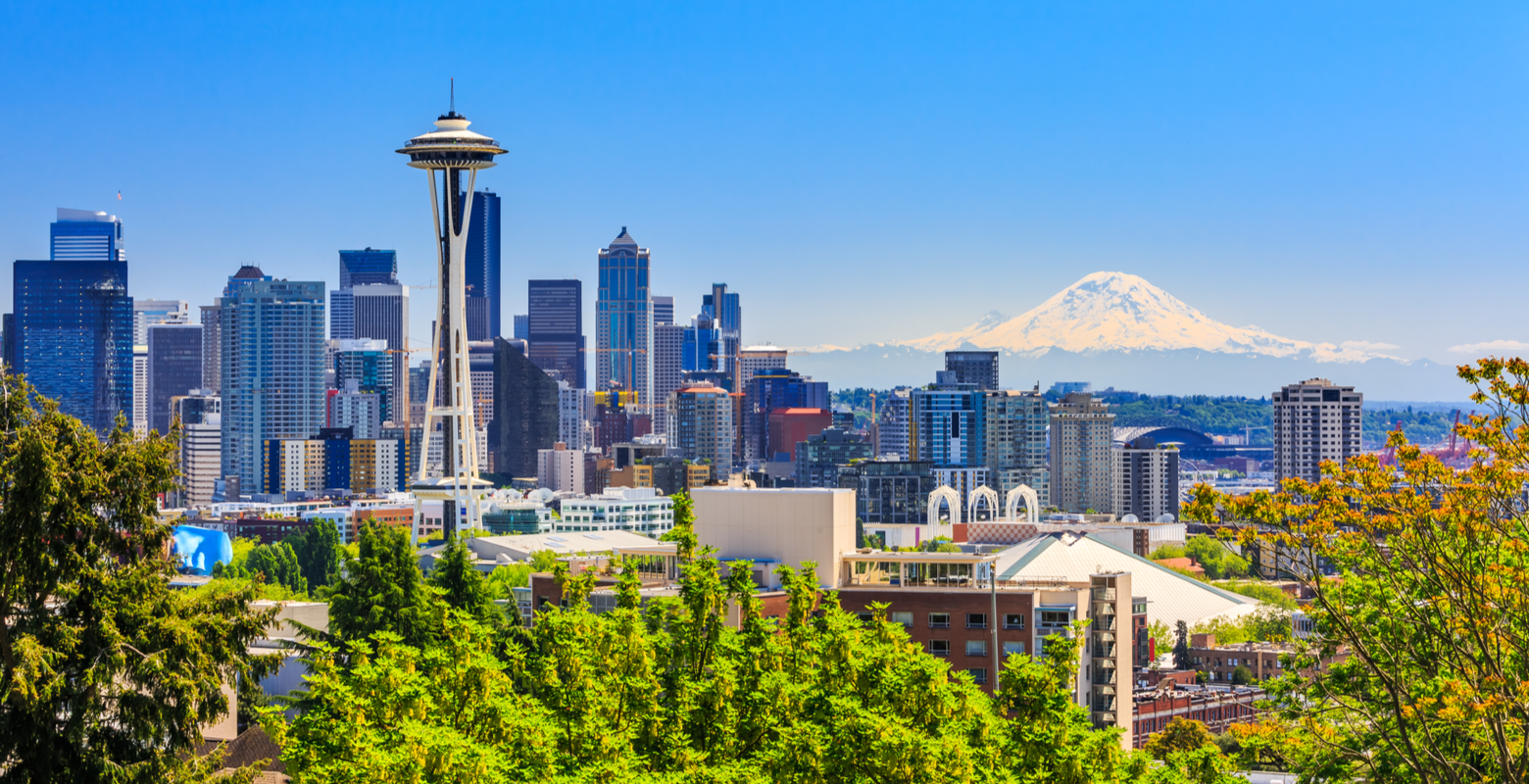 Featured image for a piece on where to stay in Seattle featuring a skyline of Seattle with the space needle and mount rainier in the background