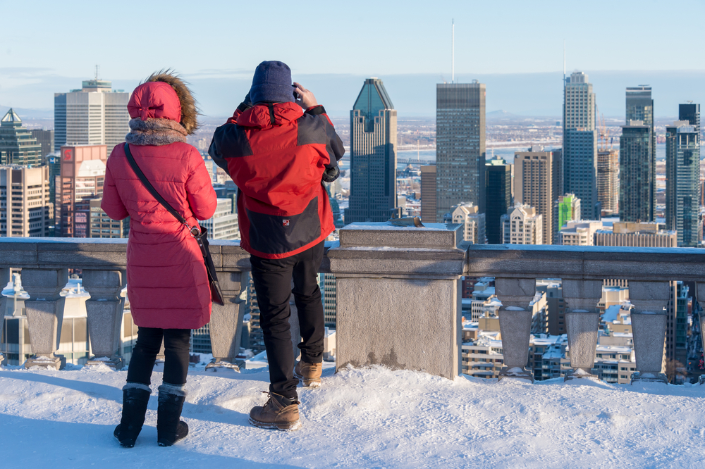 Two people standing on a rooftop looking over the downtown area for a piece on the cheapest time to visit Montreal