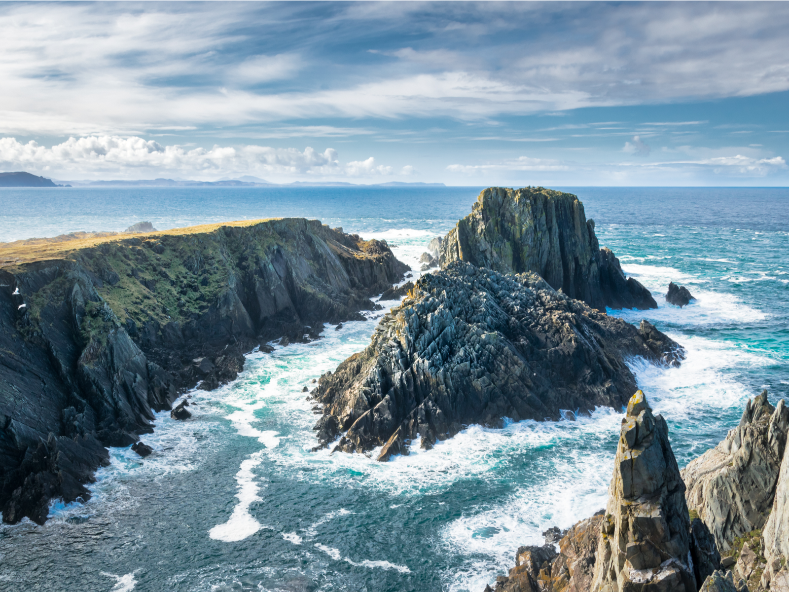 Raging Atlantic waves crashing on sea cliffs at Malin Head, one of the best places to visit in Ireland