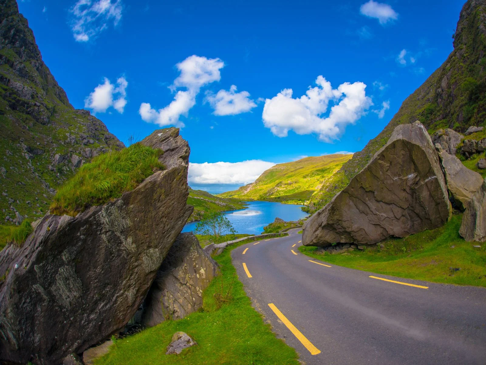 Huge boulders along a small road and a beautiful landscape at Gap of Dunloe Drive in Ring of Kerry, titled as one of the best places to visit in Ireland