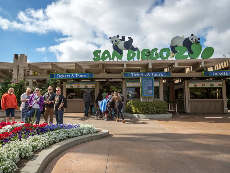For a roundup on the best zoos in the U.S., a picture of the entrance to the San Diego Zoo with a a panda sign on the top of the ticket office