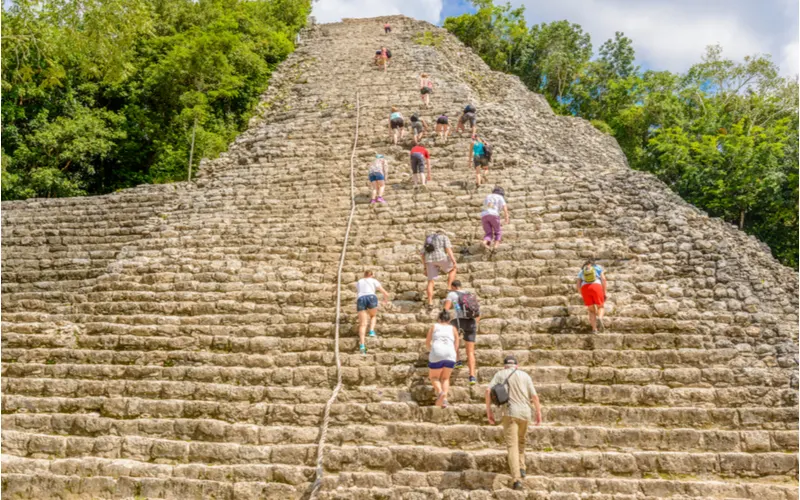 Image for a piece on the best mayan ruins in Mexico featuring a number of people scaling the pyramid in Coba