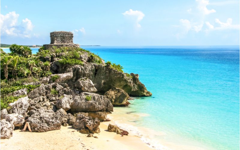 For a piece on the best Mayan ruins in Mexico, a photo of the God of Winds temple overlooking a blue ocean on a sunny day