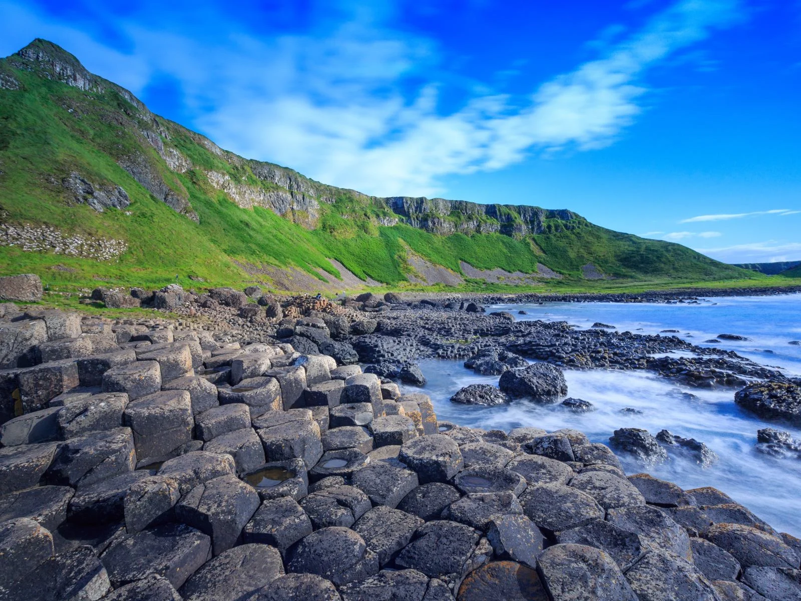 Green patches of grass and rare natural hexagonal rocks at Giant's Causeway Coast, a UNESCO Heritage Site and one of the best places to visit in Ireland