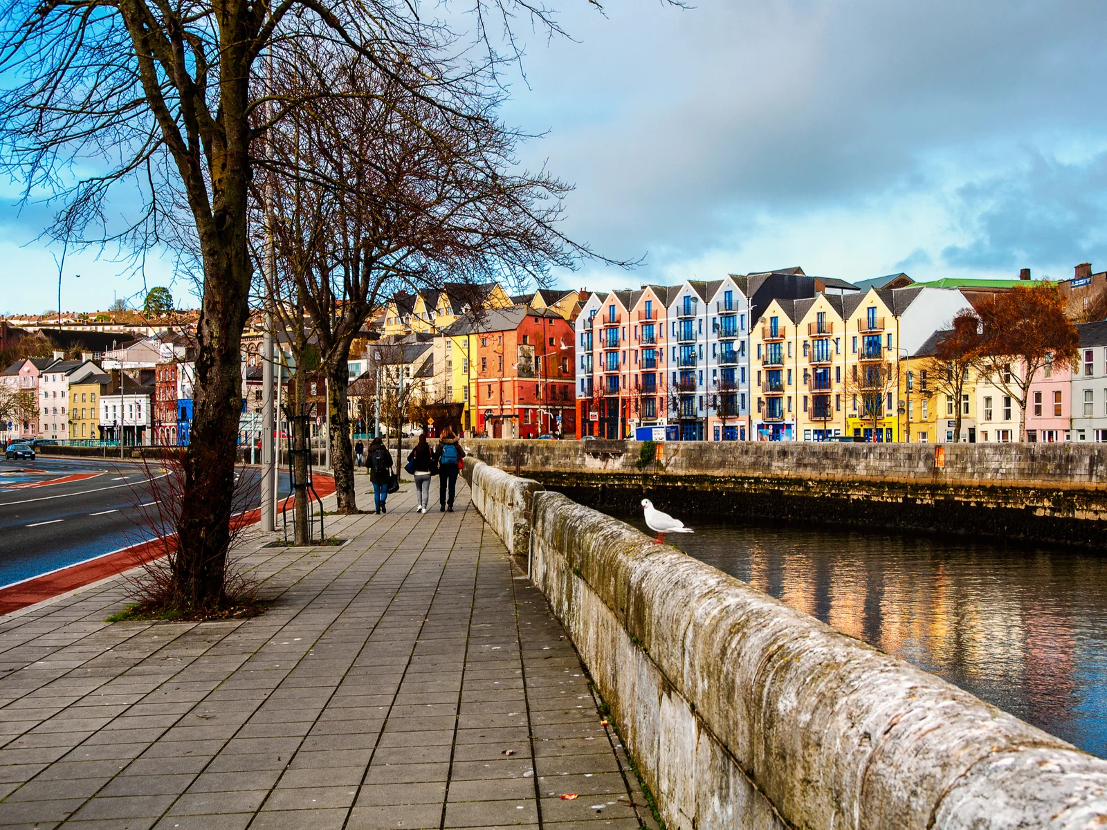 People walking on a path on the banks of a river in Cork, one of the best places to visit in Ireland