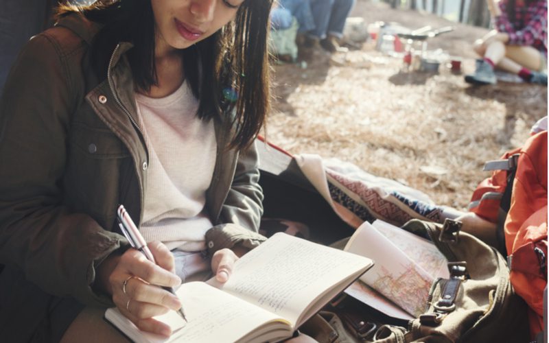 The best travel journal being used by an Asian woman in a coat