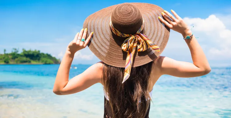 Woman wearing the best beach hat while standing by the ocean