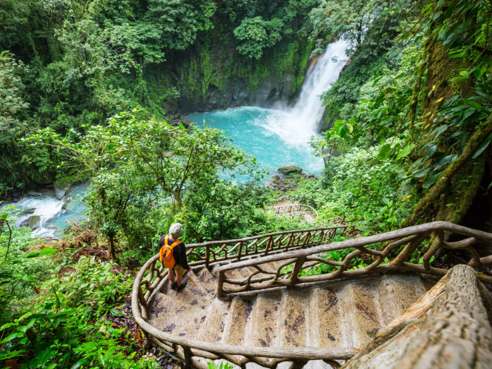 Woman looking at a waterfall in the jungle for a piece on where to stay in Costa Rica