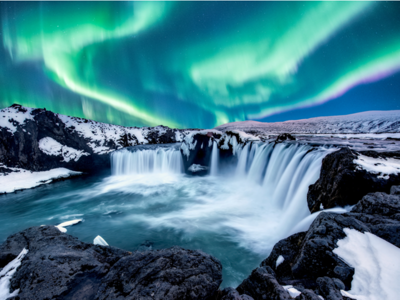 Northern lights above the Godafoss waterfall during the best time to visit Iceland