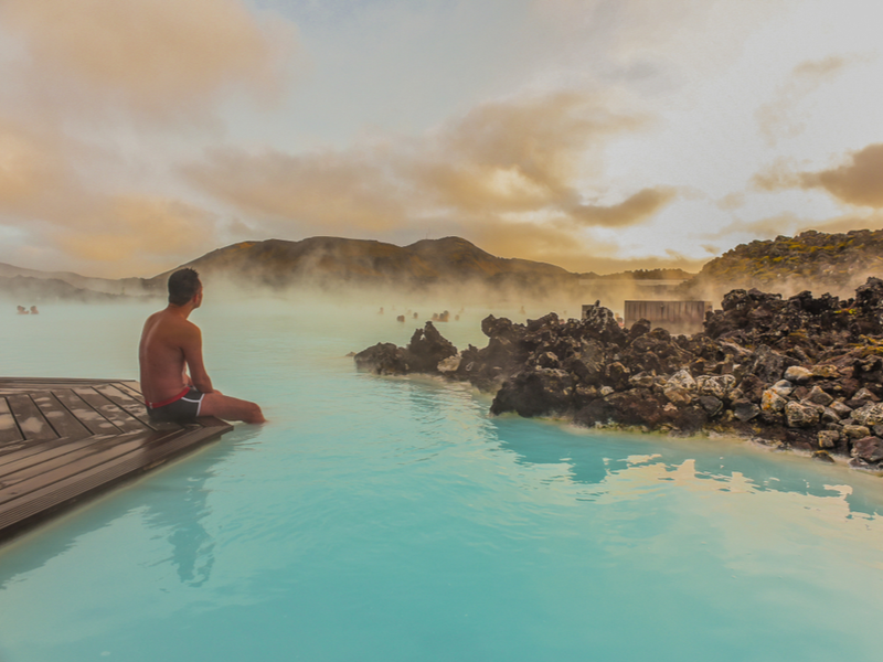 Man sitting on the edge of a hot spring during the best time to go to Iceland