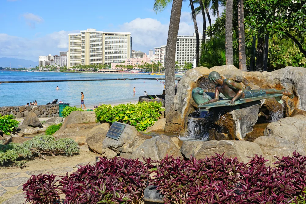 Pictured during the best time to visit Hawaii, the famous Waikiki Beach is pictured with a blue sky and hotels in the background