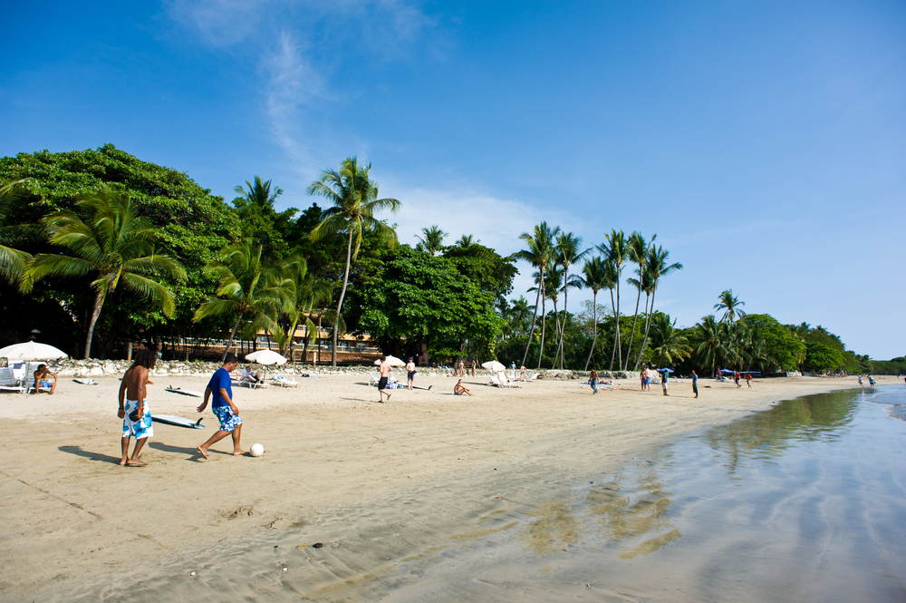 Kids playing football on the beach under a postcard-worthy sky in Guanacaste during the overall best time to visit Costa Rica