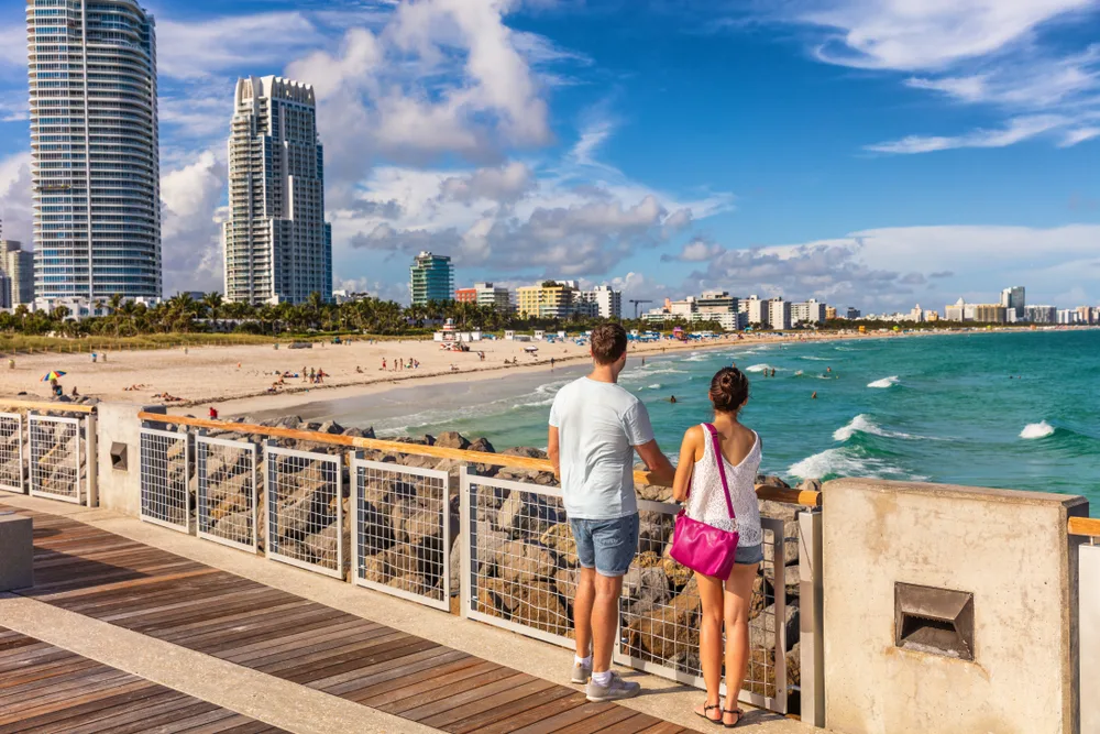 Attractive American couple standing on a boardwalk looking out over the ocean for a piece titled Where to Stay in Miami