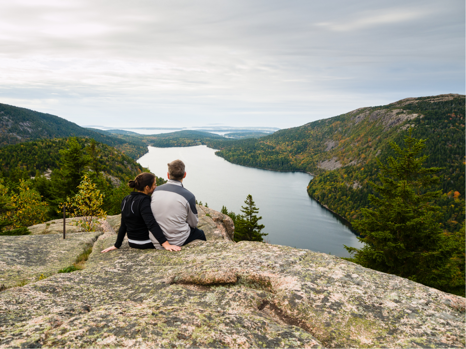 Couple sitting on a rock formation during the best time to visit Acadia National Park