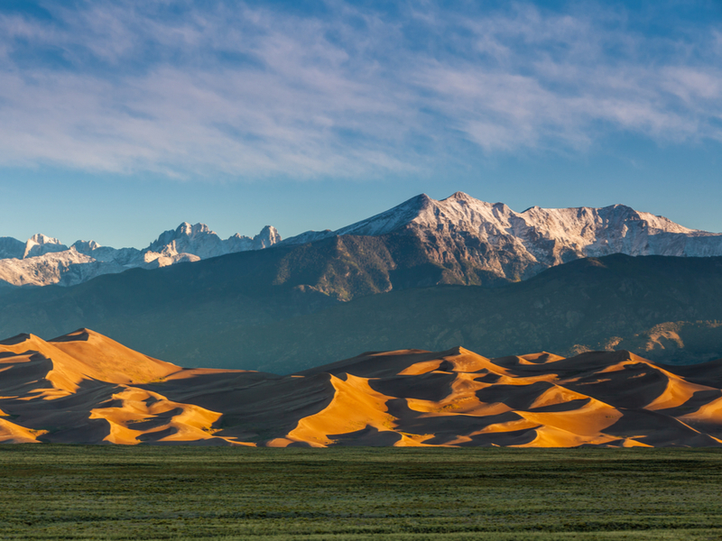 One of the best places to visit in Colorado, the Great Sand Dunes National Park and Preserve, as pictures with mountains in the background