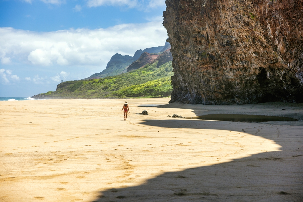 Woman walking along the Kalalau Trail on the Na Pali Coast during the best time to visit Hawaii