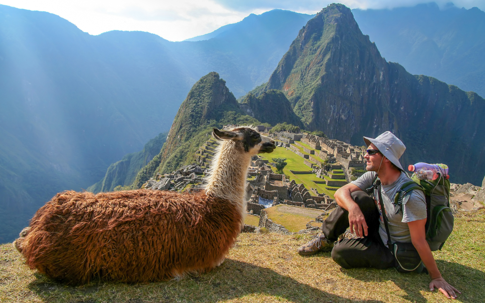 Man sitting with a llama on Machu Picchu, one of the world's best hikes
