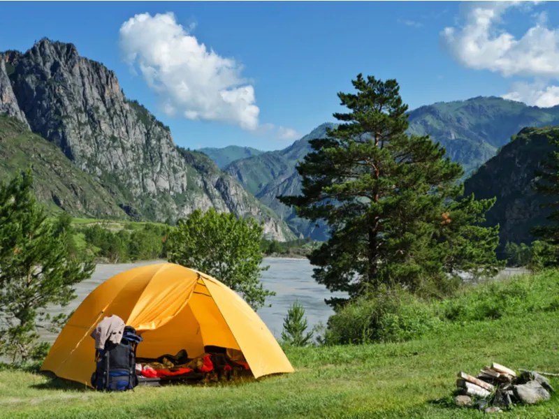 One of the best things to do in Colorado, tent camping, featuring a person in a tent in a gorge between the mountains