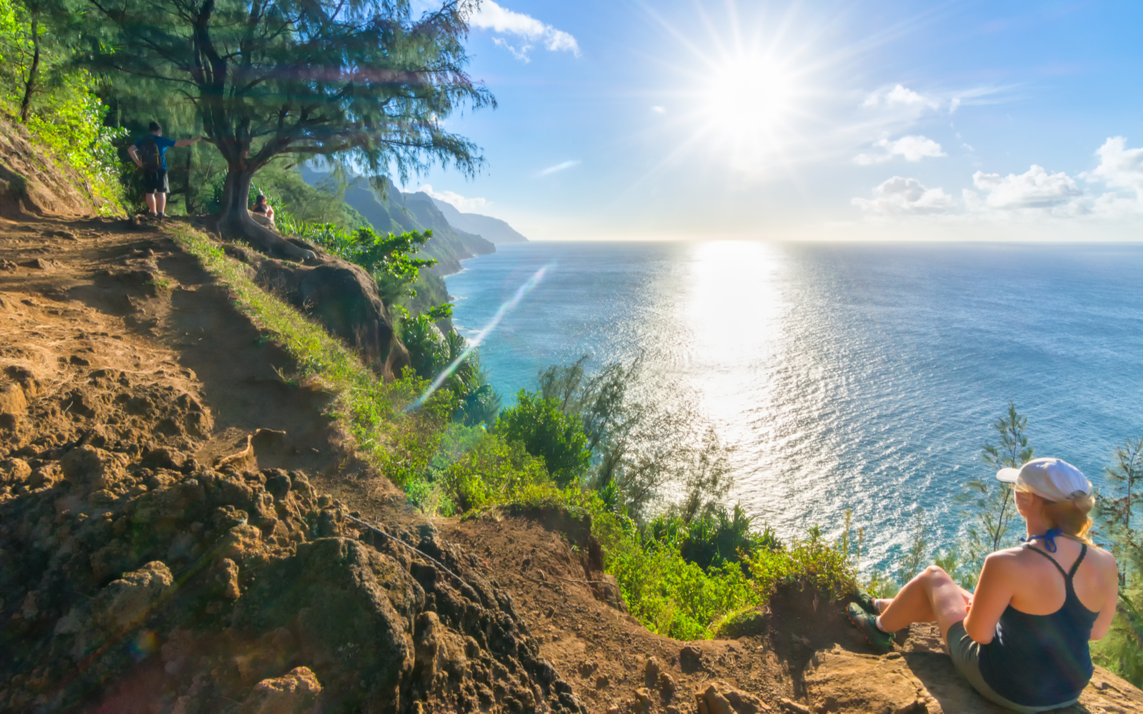 Woman sitting on the edge of a cliff on one of the best hikes in Kauai