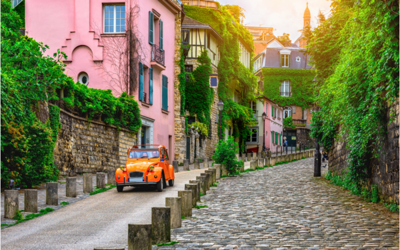 Featured image for a piece on where to stay in Paris featuring a cab driving down a street