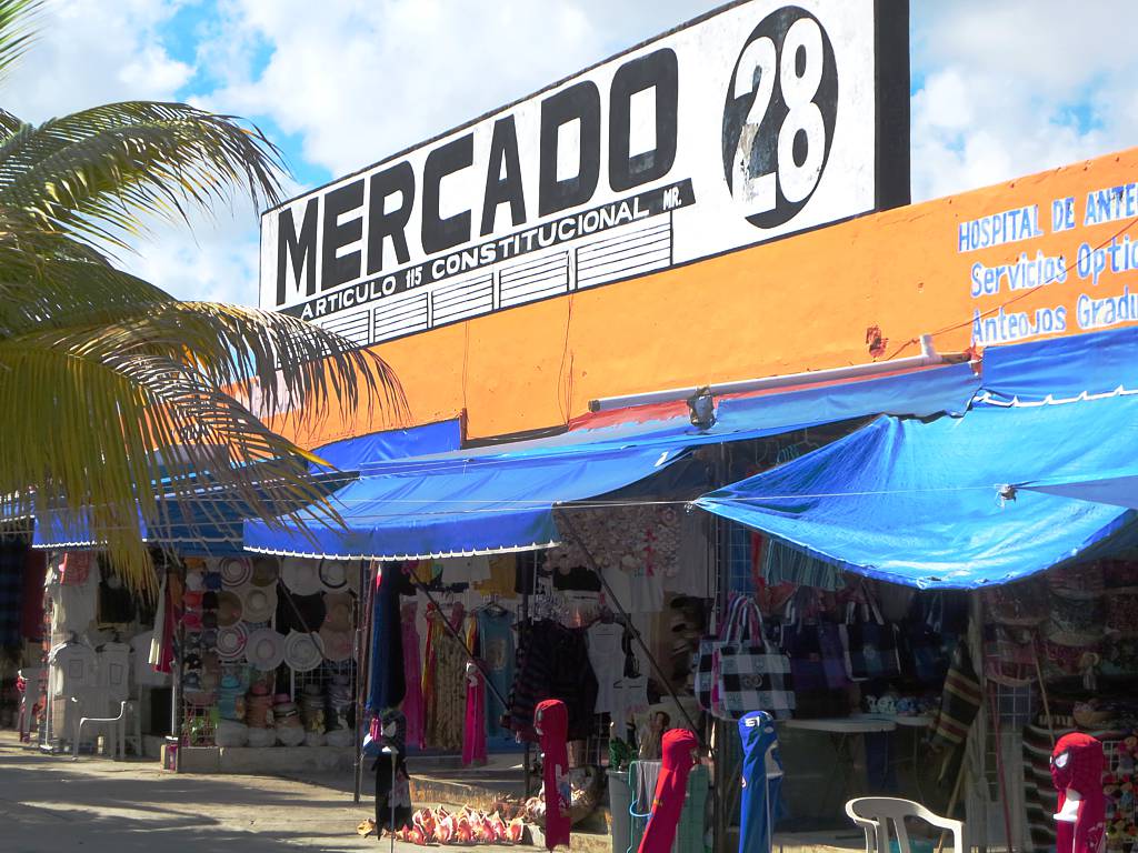 A store selling sun hats, bags, dresses, and other assorted summer items beneath the huge signage at Mercado 28, a piece on the best things to do in Cancun
