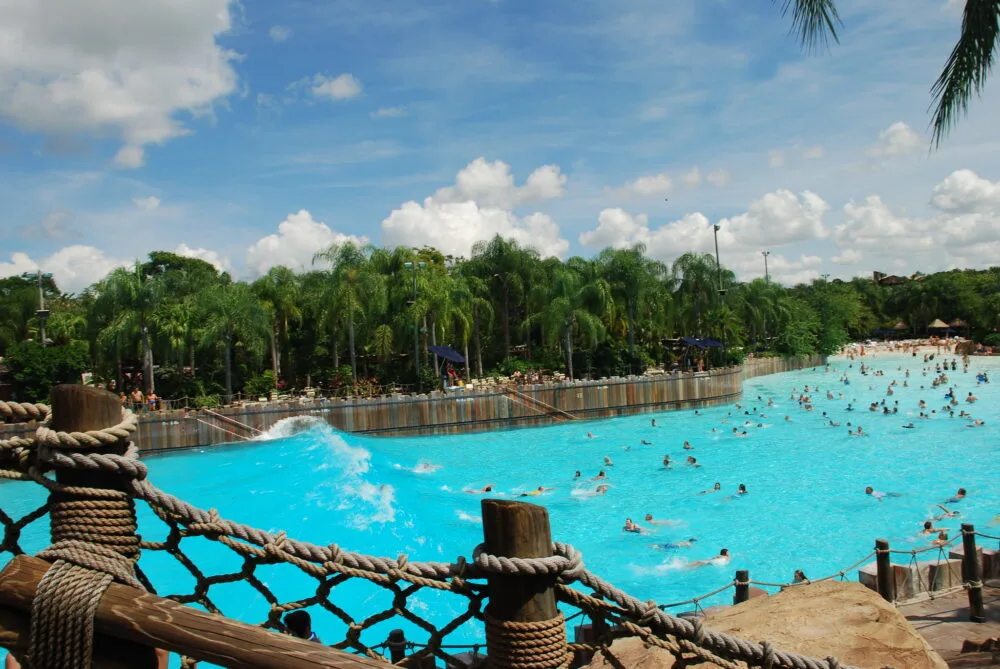 People floating on a clear wave pool at Disney's Typhoon Lagoon in Lake Buena Vista, pictured as a pice on the best water parks in the USA, with many palm trees beside the pool on a partly cloudy day
