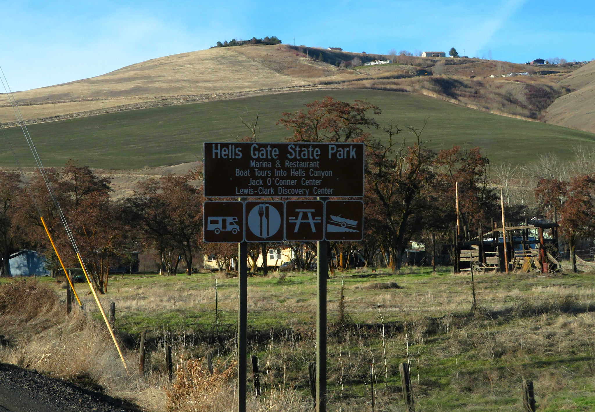 Signage of Hells Gate State Park, one of the best things to see in Idaho, with a bare mountain in background and a public recreation area
