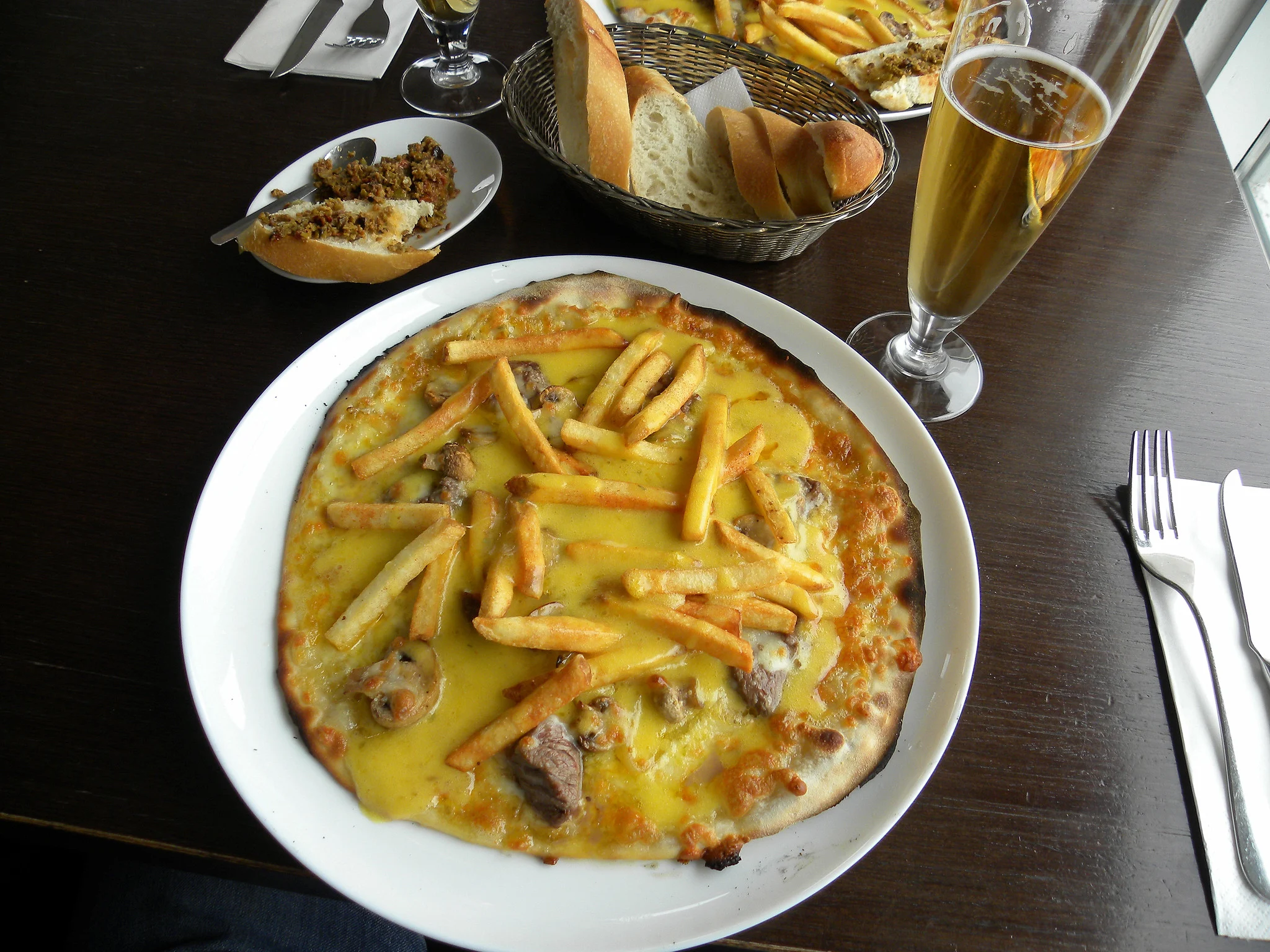Bokullupizza served on a white plate at Strikid(Strikið), considered as one of the best restaurants in Iceland, a pizza topped with beef, bernaise sauce, cheese and french fries