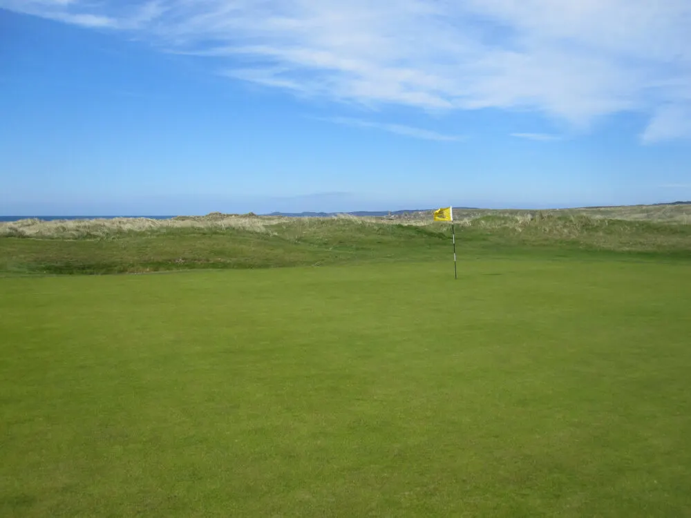 A lonely small yellow flag at a wide green golf course at Ballyliffin Golf Club in Glashedy, known as one of the best golf courses in Ireland