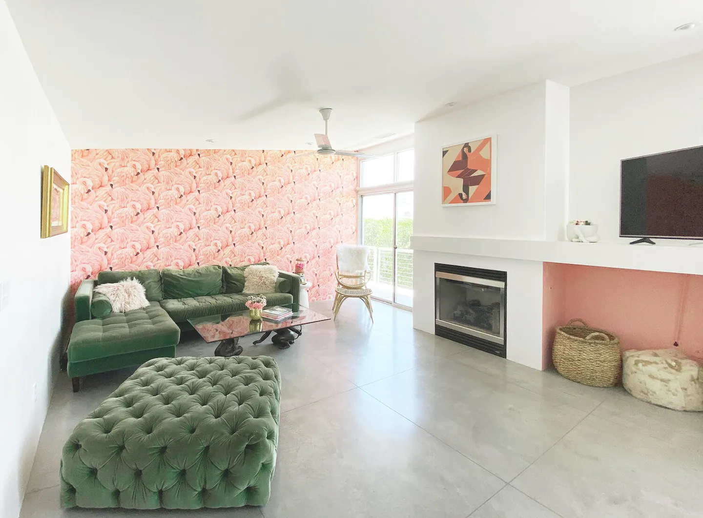 Green suede sofa set in front of the fireplace at Girls’ Getaway in Palm Springs with white painted walls and pink flamingos wallpaper, one of the best bachelorette Airbnbs