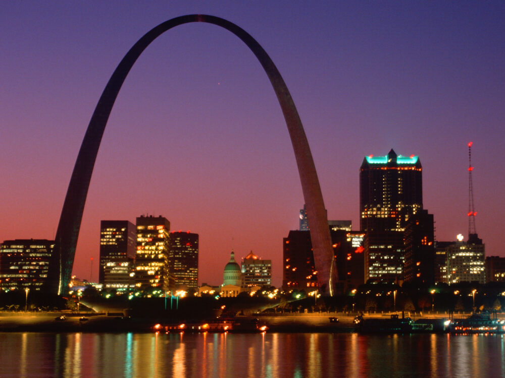 A picture of the best things to do in St. Louis, the Gateway Arch with buildings in background during dusk