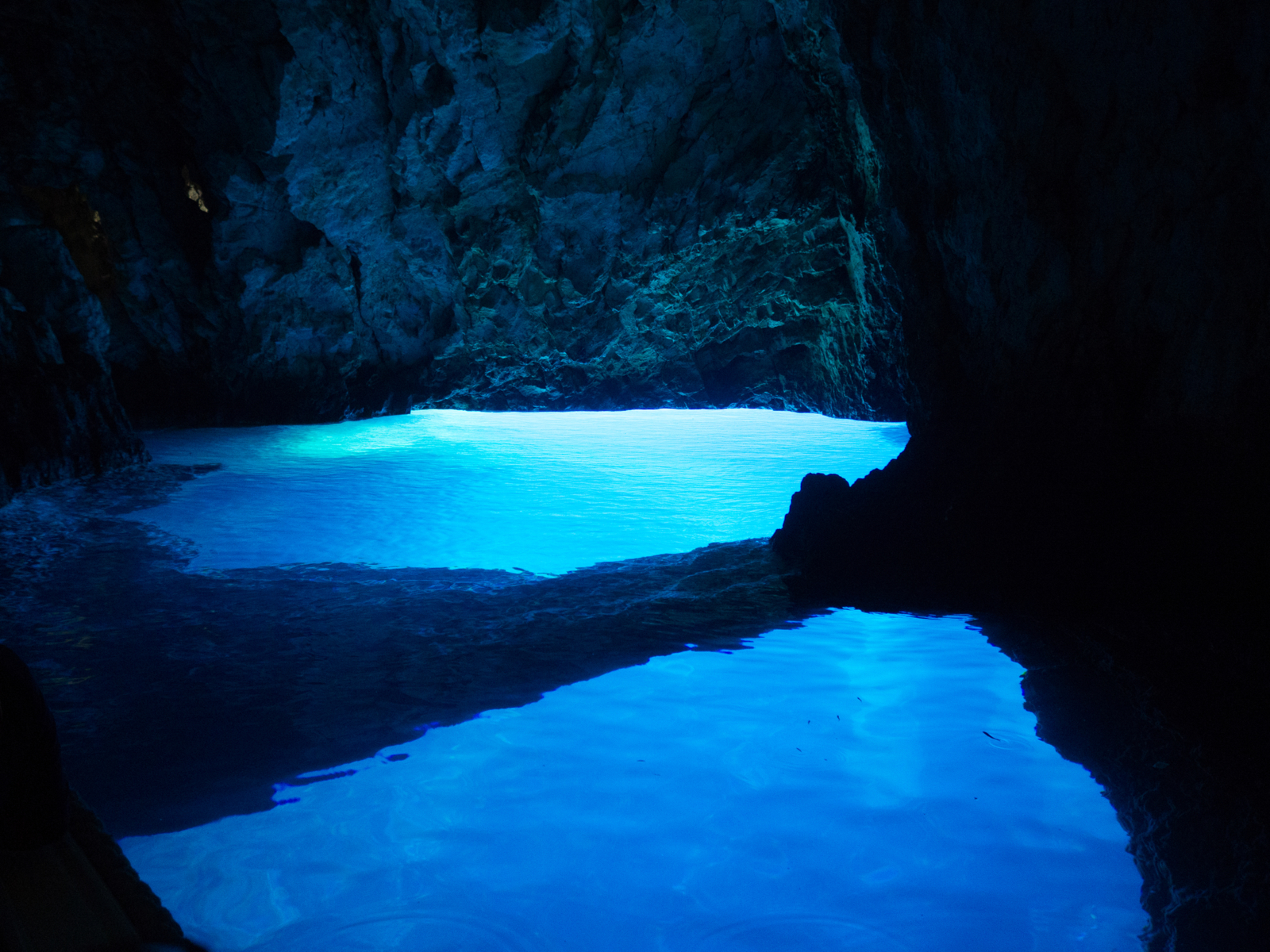 Blue Cave Grotto, one of the best things to do in Croatia, pictured during the afternoon with blue water below the rocks