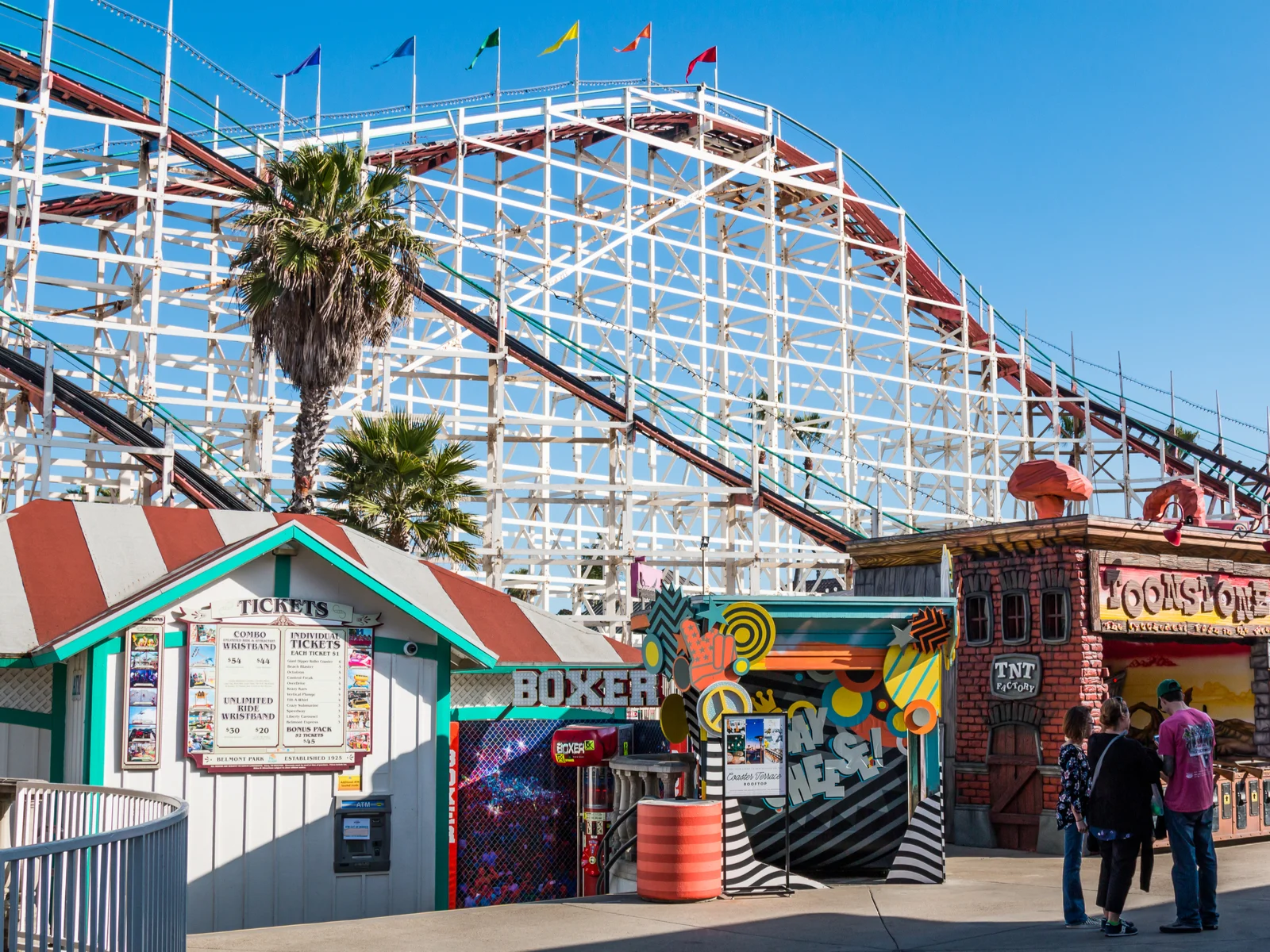 People at one of San Diego's best things to do, Belmont Park, in front of a roller coaster