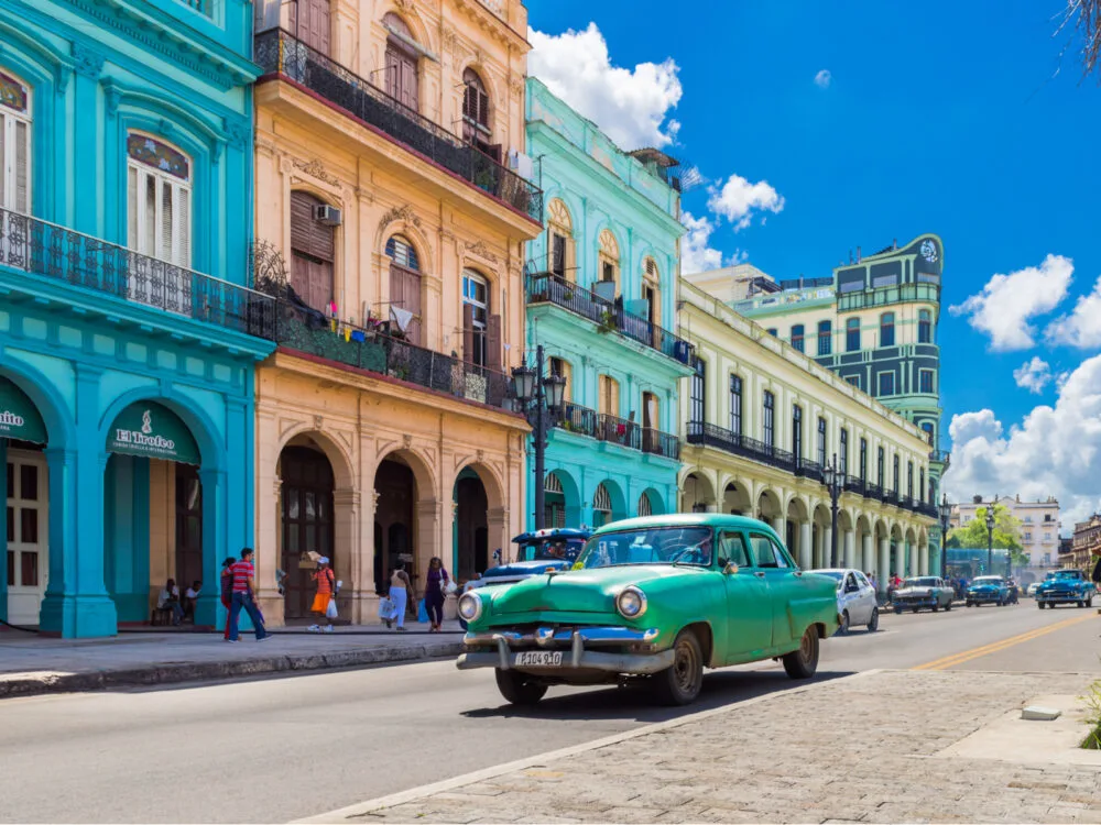 Old car in front of pastel colored buildings in one of the best places to visit in the Caribbean, Old Havana