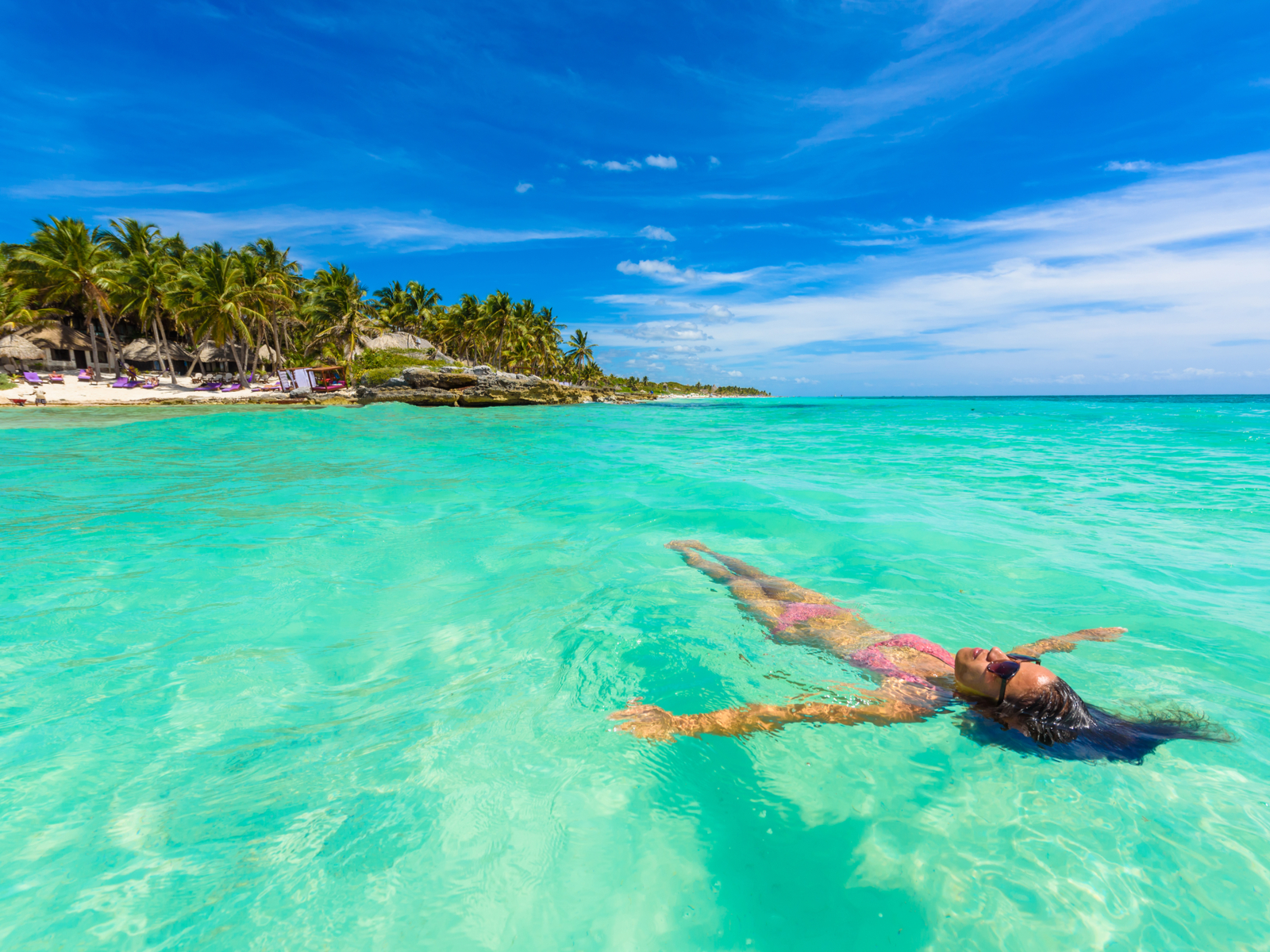 As an image for a piece titled Is Mexico Safe, a woman floating on her back in the water in Tulum