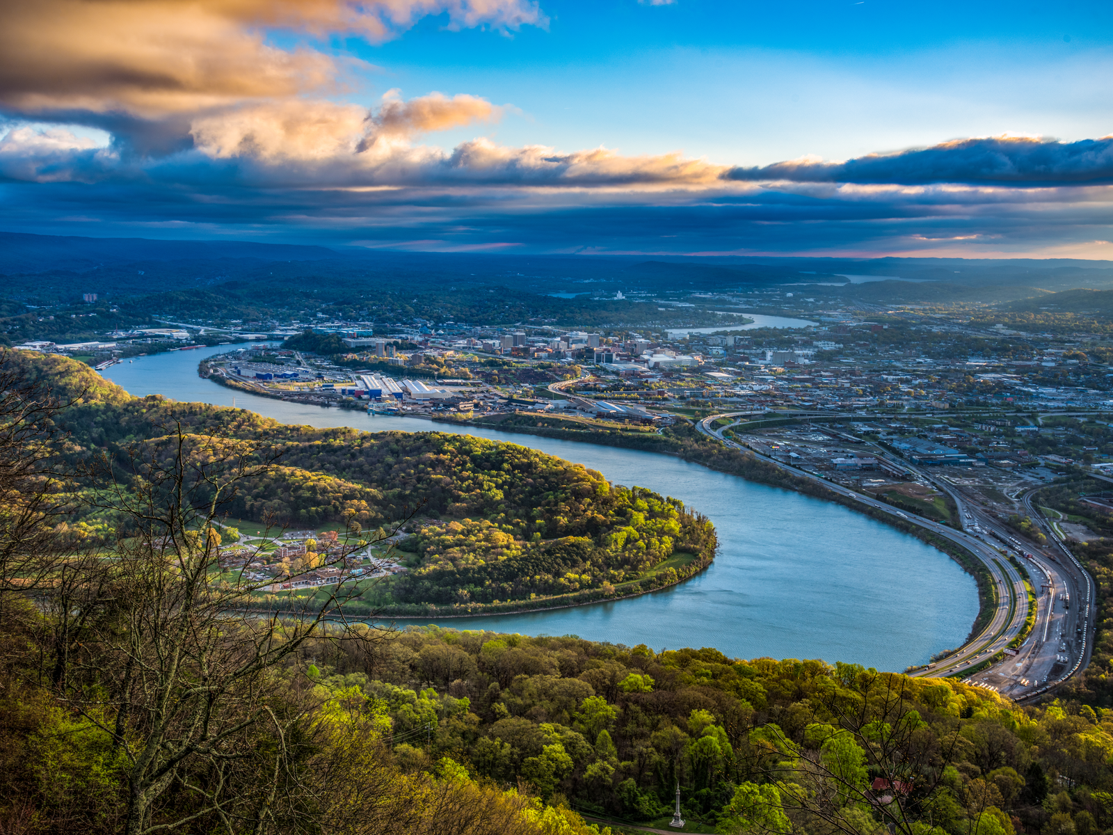 Aerial view of the winding Tennessee River and the populated Downtown Chattanooga on a cloudy afternoon, as a piece on one of the best places to visit in Tennessee