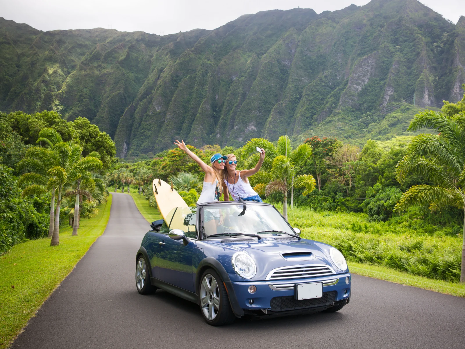 Two girls standing in the back of a convertible for a piece on the best Airbnbs in Hawaii