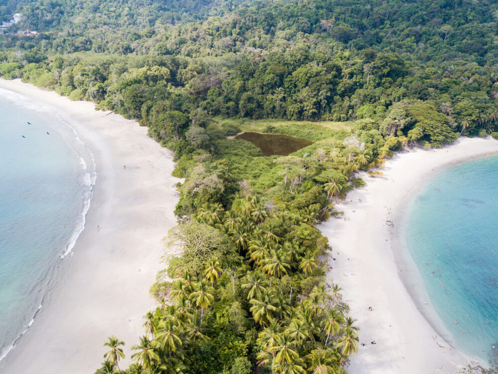 Aerial view of people swimming on the clear waters of Manuel Antonio Beach, considered as one of the best beaches in Costa Rica because of its white sand and wide shore area