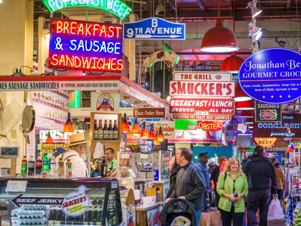 Vendors and customers in the busy Reading Terminal Market, one of the best things to do in Pennsylvania, with many signages of stores and products