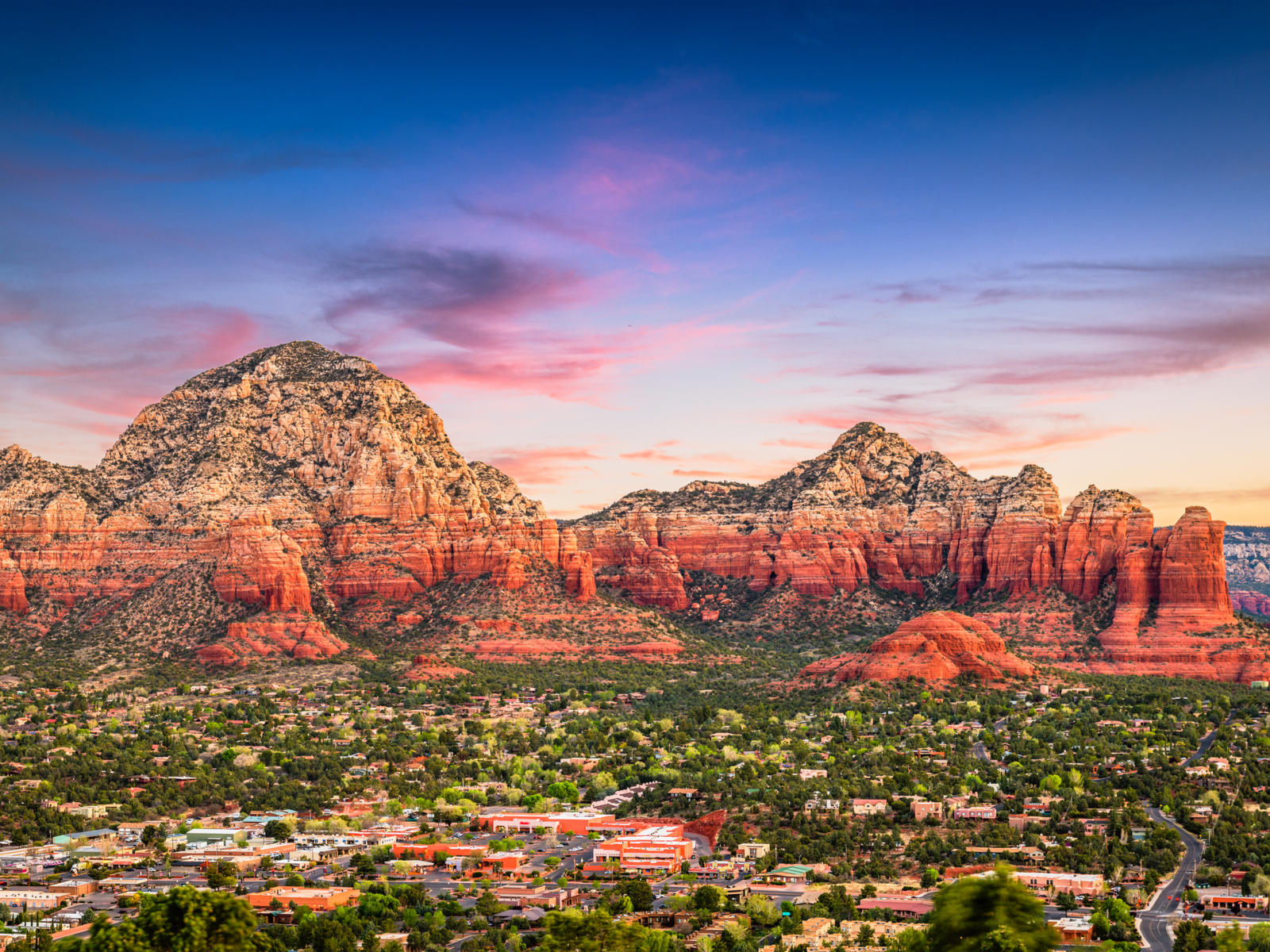 Dusk view of one of the best places to visit in Arizona, Sedona, on a clear day with a pink sky