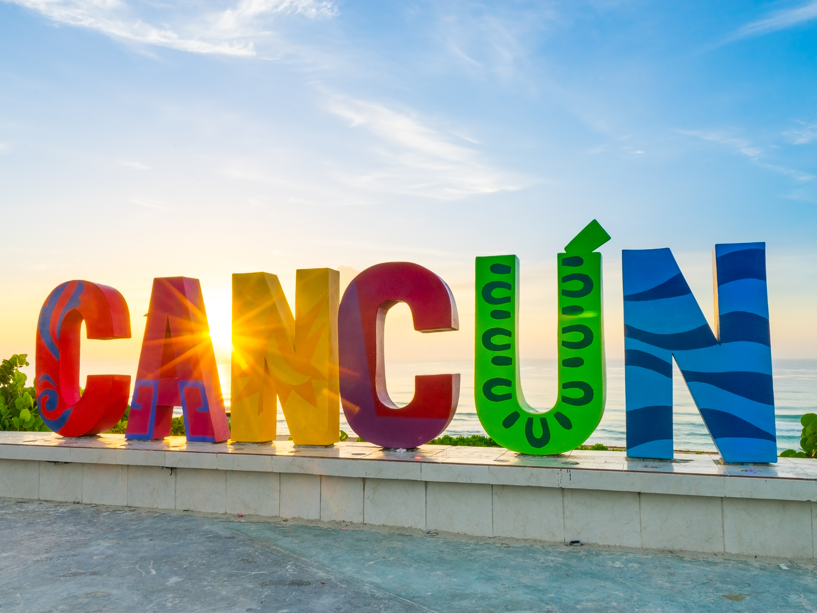 Visible sun rays shining through a huge vibrant CACUN signage as one of the best things to do in Cancun on sunrise