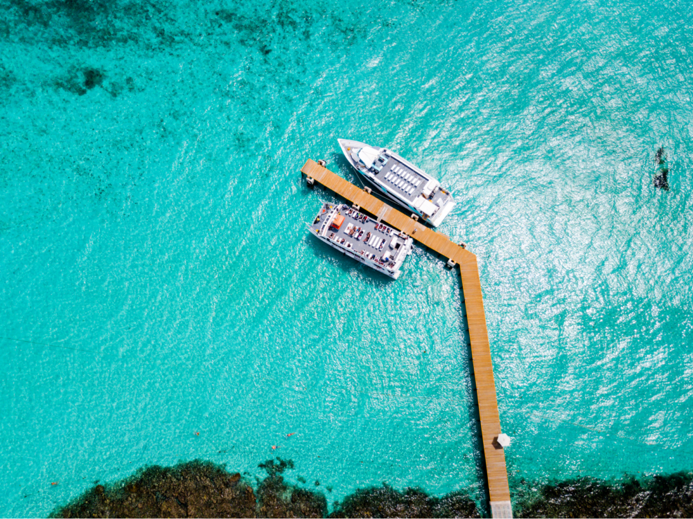 Overhead view of two touring ships docked on a clear turquoise waters at a boardwalk in Costa Mujeres, one of the best beaches in Cancun