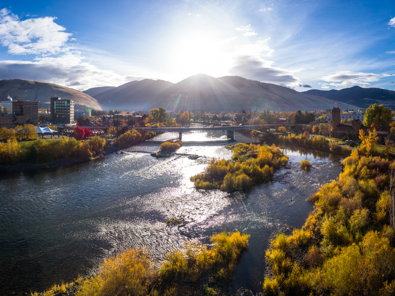 Aerial view of the Higgins Street Bridge in Missoula with mountains in the background for piece on the best places to visit in Montana