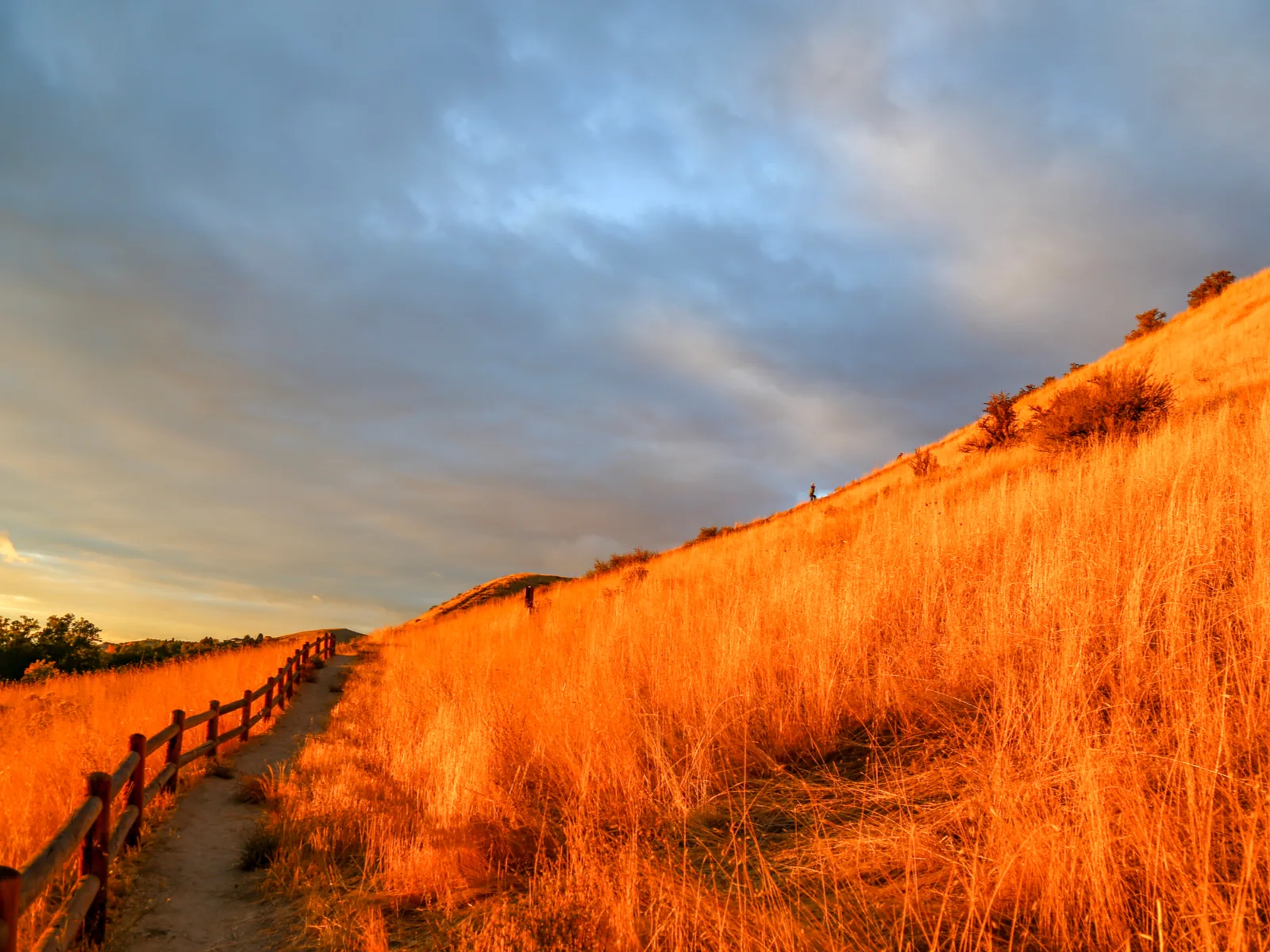 Sunset over the slop of Camel’s Back Park, one of the best things to see in Idaho, with a path guided by wooden fence