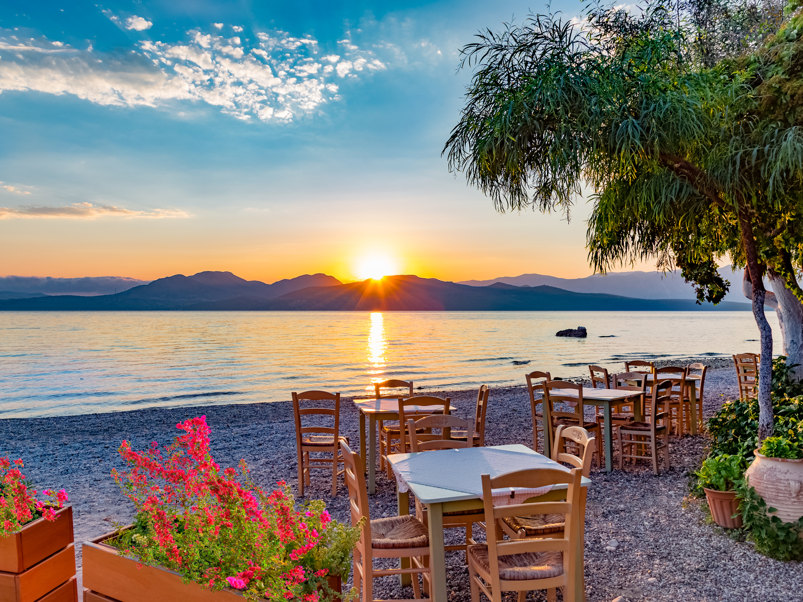 Romantic beach dining over a sunrise beside a calm sea at Lefkada Island, one of the best islands in Greece to visit