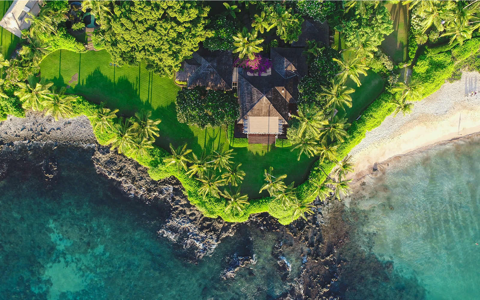 Aerial image of one of the best Airbnbs in Hawaii pictured from above with the yard running up to the coastline
