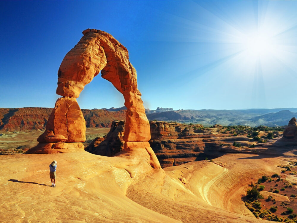 Person photographing a rock formation in Arches National Park during the summer for a piece on the best places to visit in Utah