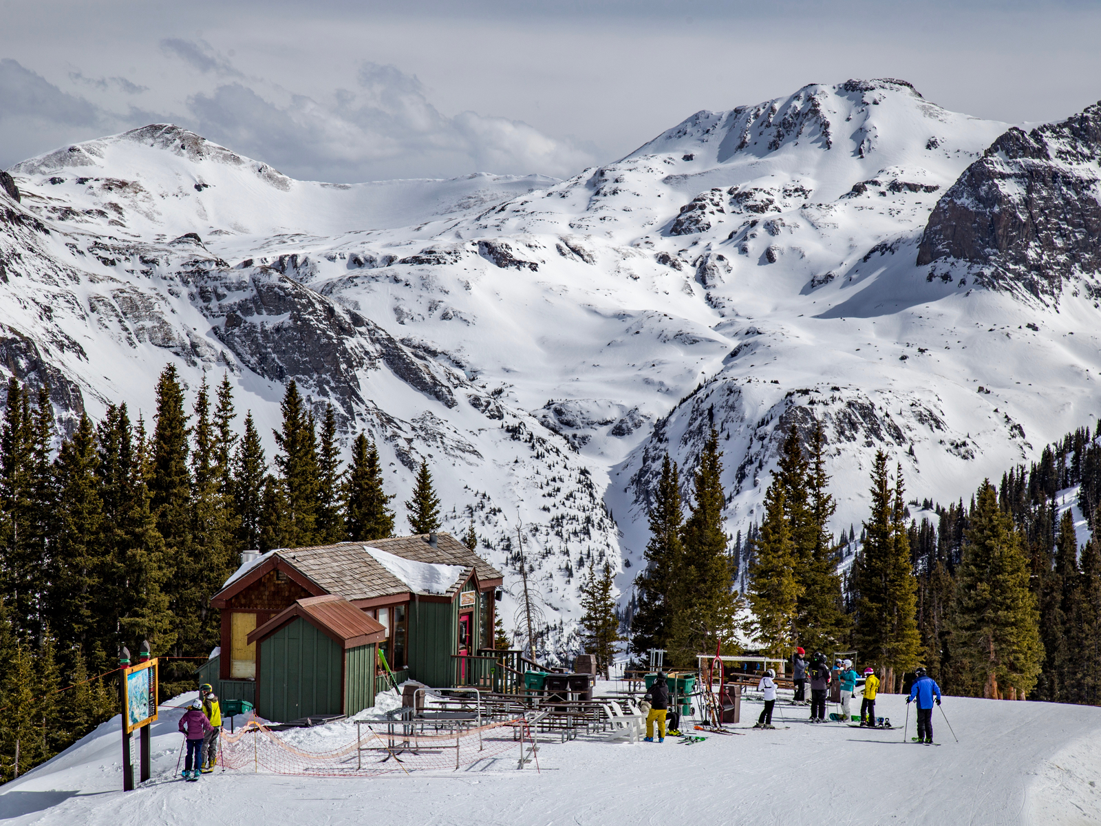 Several skiers fronting a cabin and a rest area of one of the best ski resorts near Denver, Telluride Ski Resort