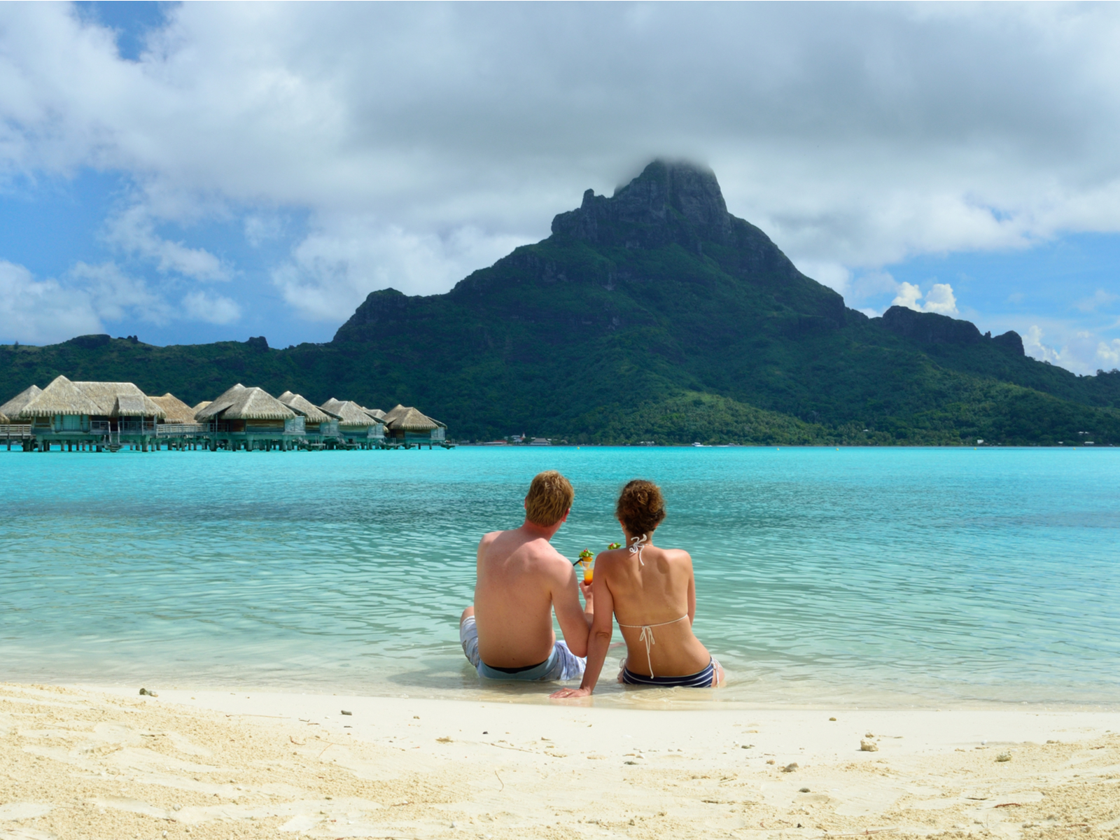 Young couple honeymooning during the best time to visit Bora Bora while looking at the lagoon